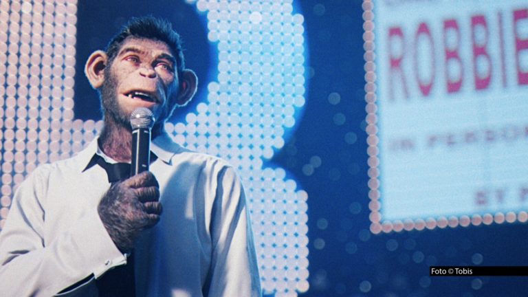 Am 2. August zeigt ProSieben ab 20:15 Uhr die deutsche Free-TV-Premiere von „Better Man – Die Robbie Williams Story". Der Film von „Greatest Showman"-Regisseur Michael Gracey erzählt das Leben des britischen Popstars, mit einem ungewöhnlichen Twist: Die Rolle des Robbie Williams übernimmt ein computergenerierter Schimpanse. Foto © TobisAm 2. August zeigt ProSieben ab 20:15 Uhr die deutsche Free-TV-Premiere von „Better Man – Die Robbie Williams Story". Der Film von „Greatest Showman"-Regisseur Michael Gracey erzählt das Leben des britischen Popstars, mit einem ungewöhnlichen Twist: Die Rolle des Robbie Williams übernimmt ein computergenerierter Schimpanse. Foto © Tobis
