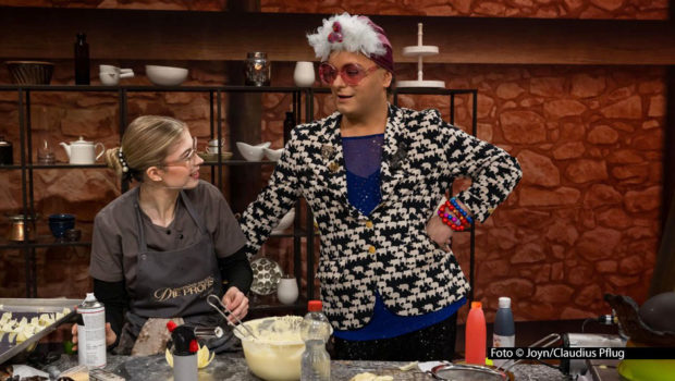 In der zweiten Staffelrunde der Sat.1-Show „Das große Backen – Die Profis“ bekommt das Jury-Trio Christian Hümbs, Bettina Schliephake-Burchardt und Günther Koerffer glamouröse Verstärkung: Entertainer Julian F.M. Stoeckel begutachtet die Schoko-Kopfbedeckung, die die Kandidaten kreieren. Foto © Joyn/Claudius Pflug