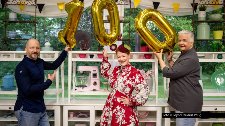 Moderatorin Enie van de Meiklokjes und die Juroren Bettina Schliephake-Burchardt und Christian Hümbs haben allen Grund zu feiern: Am 5. August zeigt Sat.1 die insgesamt 100. Folge von „Das große Backen“. Foto: Joyn/Claudius Pflug