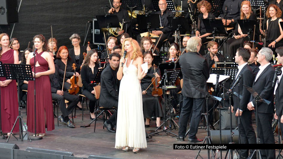 Gleich an zwei Abenden spielt das „Orchestra on the Rocks“ bei den Eutiner Festspielen 2025. Rock-, Pop- und Musical-Songs im symphonischen Gewand. Mit dabei ist Sonya Kraus, die als Moderatorin durch den vielfältigen und vom Publikum umjubelten musikalischen Abend führt.Foto_Eutiner-Festspiele
