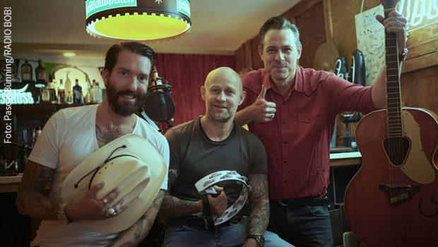 Im Interview mit den The BossHoss-Frontmännern Alec Völkel und Sascha Vollmer hat Schauspieler Jürgen Vogel auch einiges über seine musikalische Vergangenheit zu erzählen. Am Samstag läuft die Sendung „Rodeo Radio – The BossHoss Rockshow“ auf RADIO BOB!. (Foto: Pascal Bünning/RADIO BOB!)